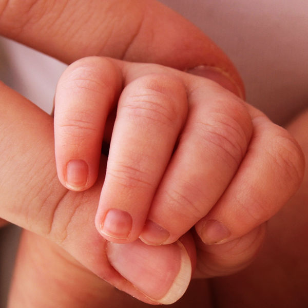 A baby's hand grasping an adult finger